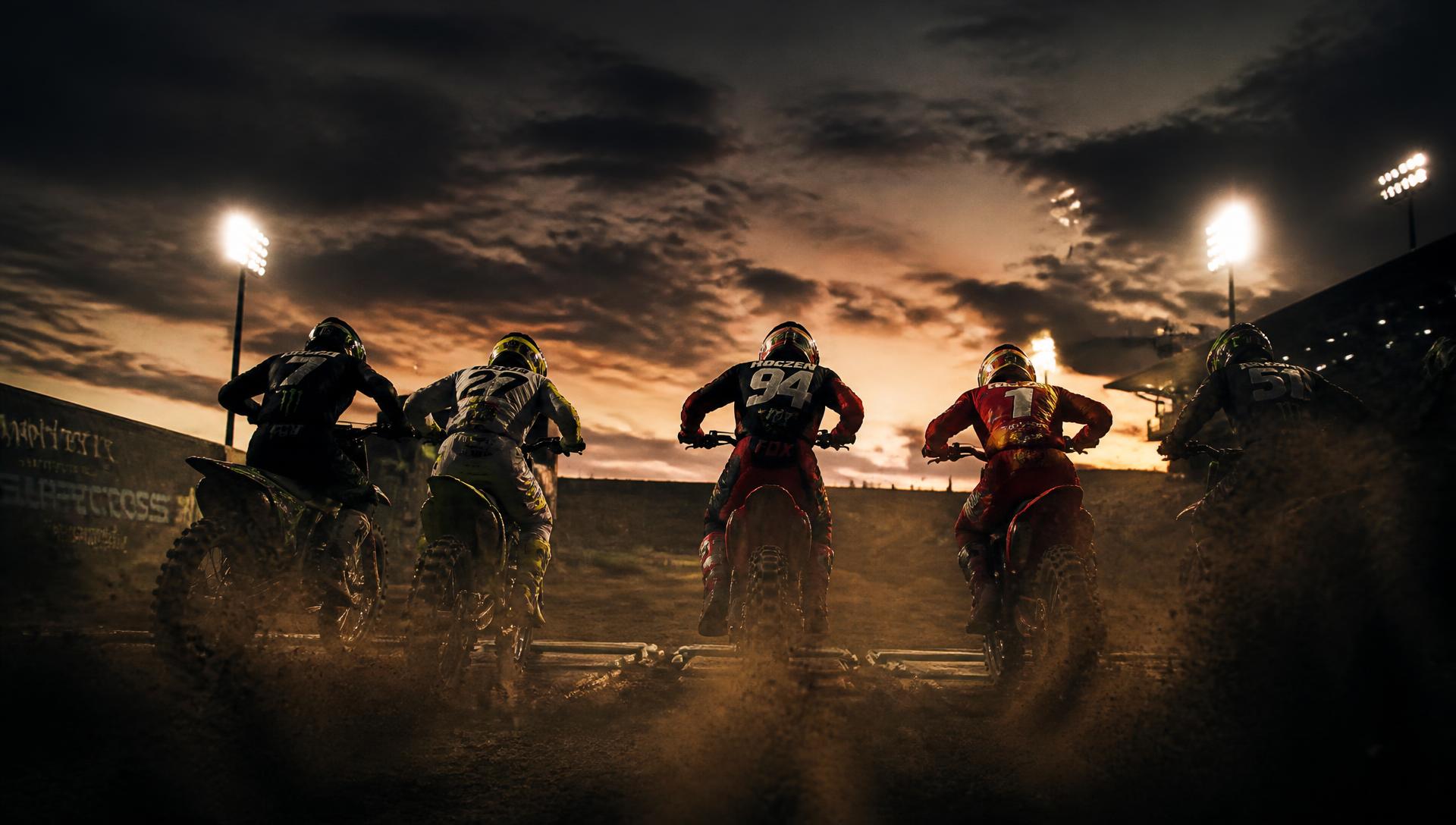 Motocross riders leaving the start gate at dusk